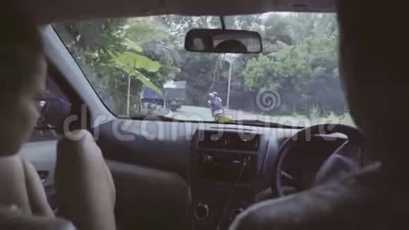 男人和女人坐在车里骑在东部热带农村的某个地方视频的预览图