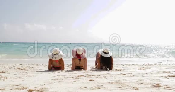 三个女孩躺在沙滩上的后视角享受阳光女性游客在暑假视频的预览图