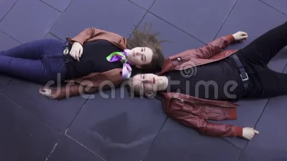 漂亮的男人和女孩穿着浅棕色夹克躺在深色瓷砖地板上视频的预览图