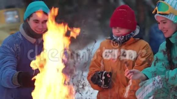 冬季森林一家人坐在火炉旁煎香肠视频的预览图