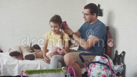 年轻的父亲花时间和他的小女儿在一起爸爸编辫子和她一起玩还有傻瓜视频的预览图