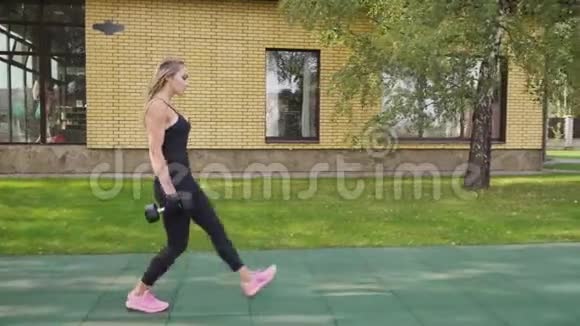成年健身妇女在运动场上用哑铃做行走视频的预览图