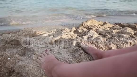 海滩上女孩的腿海上日落海浪海风沙滩视频的预览图