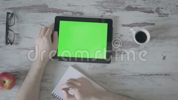 男性手在笔记本上做笔记其次是一个绿色屏幕的平板电脑视频的预览图