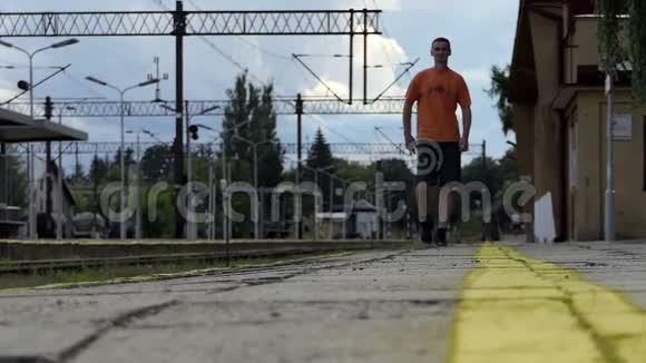 夏天一个年轻人在slomo沿着铁路站台走视频的预览图