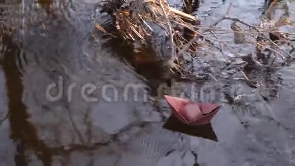 沿着河岸棕色的纸船在清澈的水中航行视频的预览图