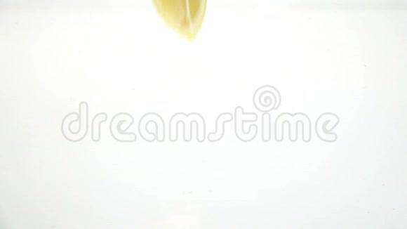 四分之一的柠檬滴在水里然后留在那里白色背景慢动作视频的预览图