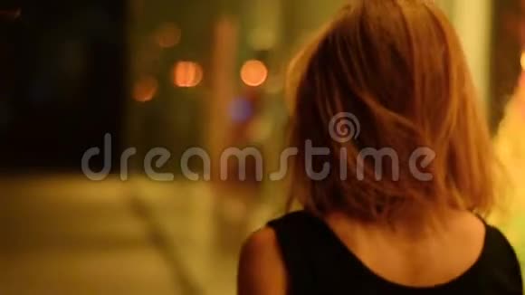 美丽的女人调整头发看着相机晚上去城市视频的预览图