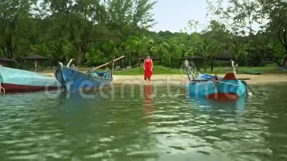 那个女人在越南的海滩上接近水岛上海岸的传统蓝色渔船视频的预览图