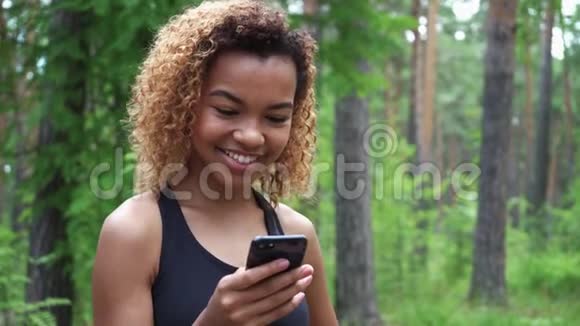 年轻的黑人妇女在慢跑后使用智能手机并将绿色屏幕显示到相机上视频的预览图