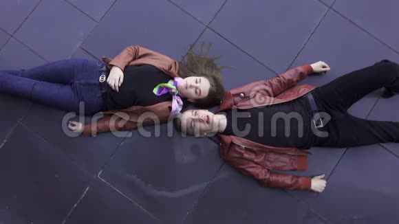 可爱的男人和女孩穿着浅棕色夹克躺在深色瓷砖地板上视频的预览图