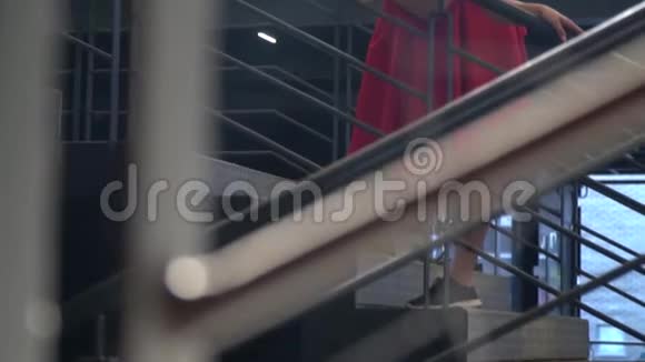 一个穿着红色裙子和黑色上衣的女孩被抓在商场的楼梯栏杆上有点慢动作视频的预览图
