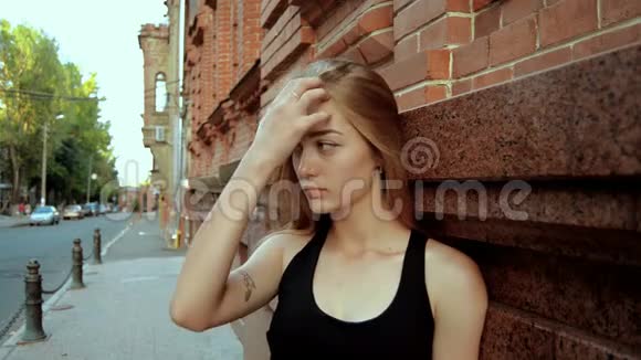 美丽的金发女郎站在街上把你的头发弄直视频的预览图