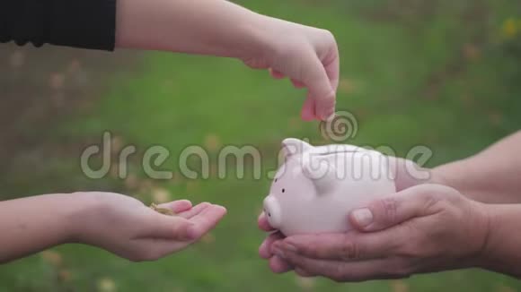 母女俩把硬币放进储蓄罐里女人拿着储蓄罐女孩把硬币放在户外视频的预览图