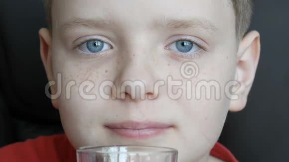 小男孩蓝眼睛雀斑从玻璃烧杯里喝牛奶擦他的奶胡子视频的预览图