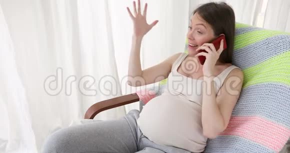在窗户附近打电话的孕妇视频的预览图