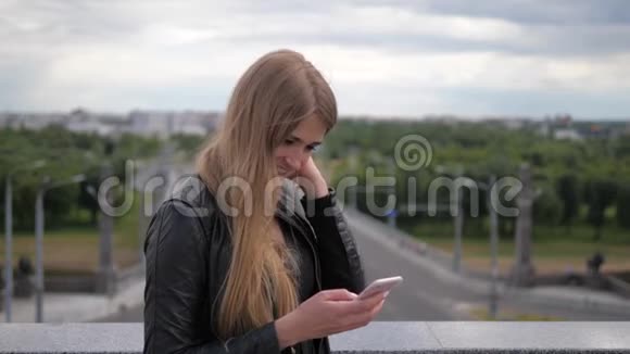 开朗的心上人年轻的金发女郎使用智能手机视频的预览图