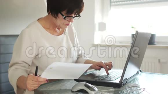 商业女性使用电脑互联网支付网上银行支付账单她手里拿着笔和纸视频的预览图