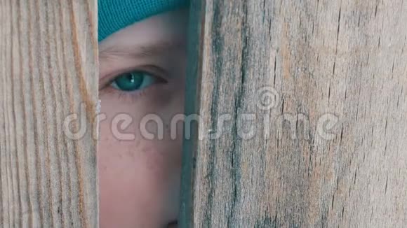 一个十几岁的男孩惊恐地凝视着门槽或栅栏的缝隙视频的预览图