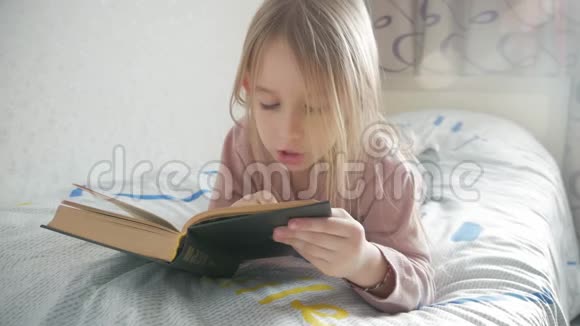 女孩躺在床上看书女孩孩子长发可爱睡衣放松和阅读童话书惬意的时光视频的预览图