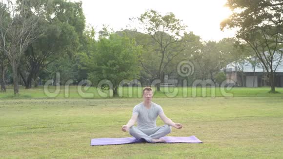 年轻英俊的男子闭着眼睛在公园沉思视频的预览图