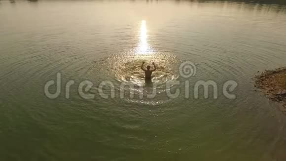 日落时分一个年轻人用双手在湖里泼水视频的预览图