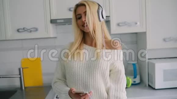 无忧无虑的年轻女子在厨房里听音乐跳舞视频的预览图