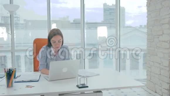 无聊的女商人在办公室里用现代笔记本电脑工作视频的预览图