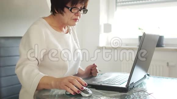 一位老年妇女用笔记本电脑和银行卡支付账单在线支付远视视频的预览图