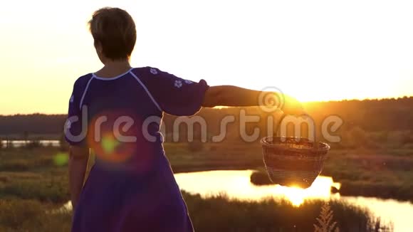 夕阳西下幸福的女人在湖岸旋转一个民间篮子视频的预览图