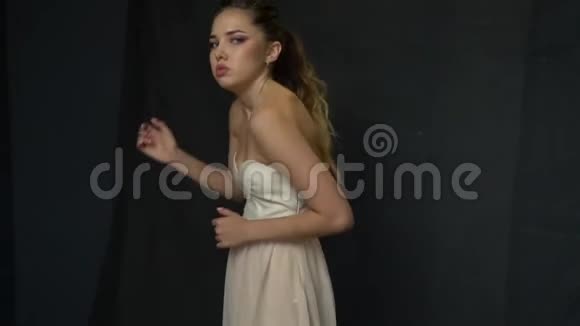 穿着白色裙子摆在画室里摆着与众不同的姿势的女孩视频的预览图