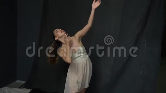 拍摄过程中一个留着长发和一件白色连衣裙的女孩正在演播室里跳舞动作缓慢视频的预览图