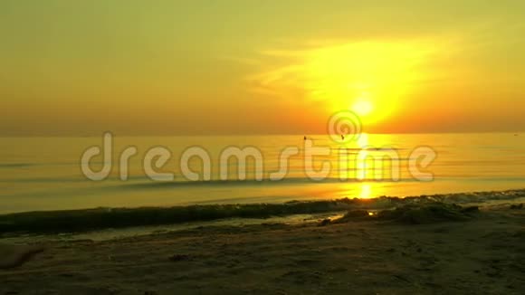 女孩正光着脚在夕阳背景下沿着沙滩散步女孩在缓慢地走着视频的预览图