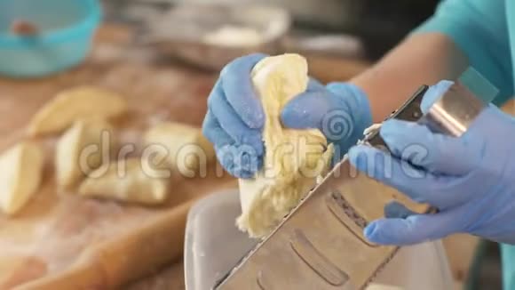 手面包师在面包房厨房的烤架上擦奶酪做馅饼视频的预览图