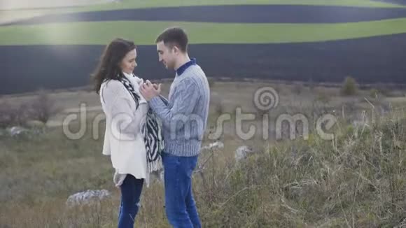 快乐的一对夫妇站在岩石上在刮风的日子里抚摸和亲吻4K视频的预览图