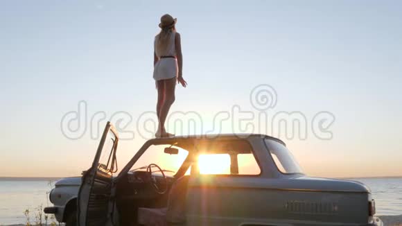 夕阳西下女性慢动作地举起手臂年轻女性站在车顶情绪激动视频的预览图