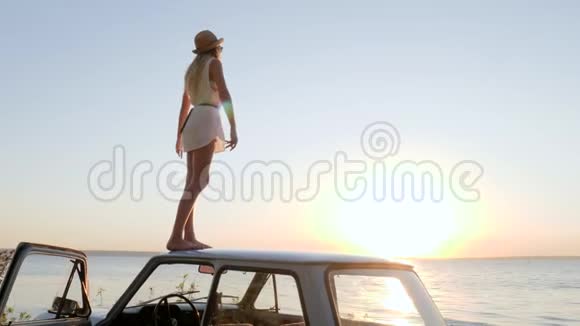 站在车顶上的女孩双手张开享受日落享受海边的自由视频的预览图