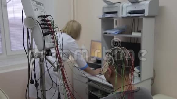 一个男性病人坐在椅子上他的头和手连接着医疗设备和健康传感器视频的预览图