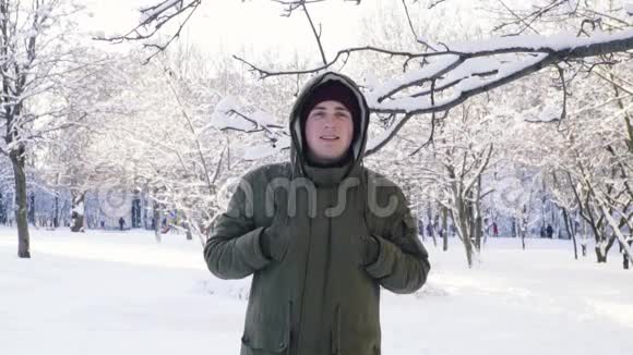 雪从树枝上落下一个人用兜帽遮住他的头慢动作视频的预览图