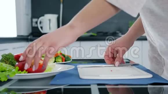 女人手拿刀切甜红辣椒做切割板上的沙拉健康食品视频的预览图