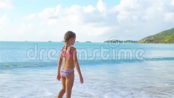 日落时分一个活跃的小女孩在海滩上做车轮流动人口视频的预览图