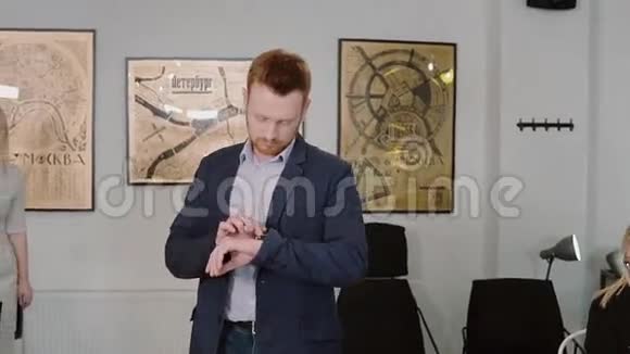 年轻人穿过办公室使用智能手表应用程序商人摸着屏幕微笑慢动作视频的预览图