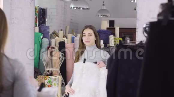 一个年轻女孩在工作室的镜子旁边选了一块布做衣服视频的预览图