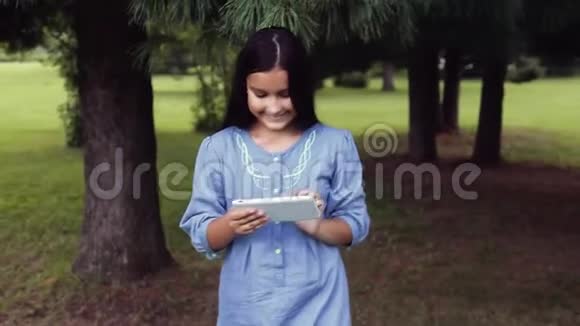 肖像一个美丽的女孩正在大自然中用平板电脑行走视频的预览图