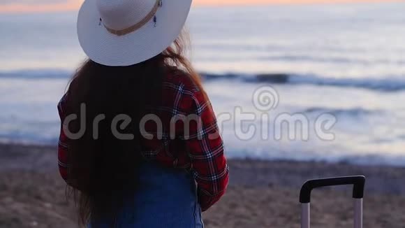日落或日出时在海滩拍照的年轻女子视频的预览图
