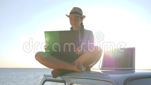 年轻女子在阳光下坐着老式汽车背景海滩上的电脑用电池供电视频的预览图