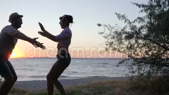 日落时分女孩在雄鸟上跳到河堤在海边剪影快乐的恋人视频的预览图