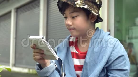 泰国男孩在花园里用剪刀剪绿色树枝视频的预览图
