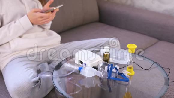 准备吸入雾化器口罩和药品放在玻璃桌上无法辨认的女人带着手机视频的预览图