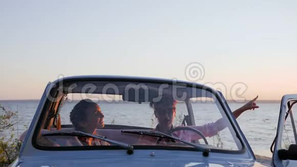 女朋友在汽车上说话指着大海的天际线朋友在沙龙机上指着河堤视频的预览图